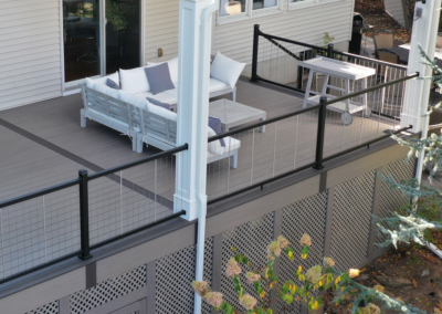 Deck in Westwood using composite decking and cable railings with a louvered pergola and lattice skirting