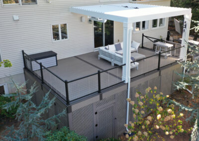 Deck in Westwood using composite decking and cable railings with a louvered pergola and lattice skirting